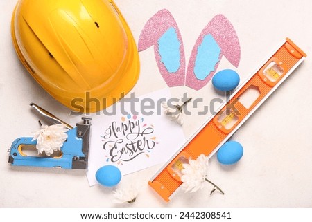Composition with greeting card, construction tools and Easter decor on light background