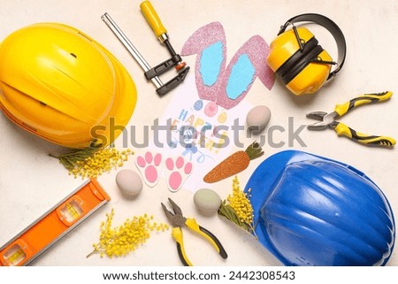 Composition with greeting card, construction tools and Easter decor on light background