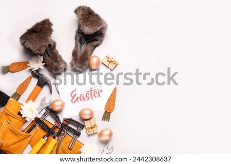Composition with construction tools, greeting card and Easter decor on light background