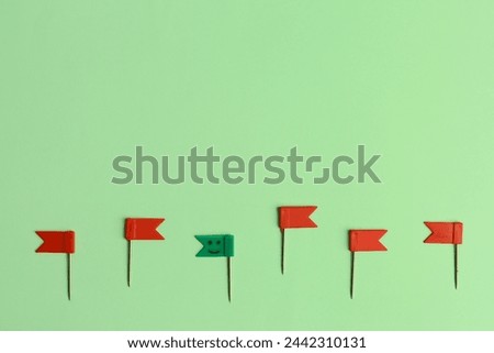 Green paper pin with drawn happy face among red ones on color background. Concept of uniqueness