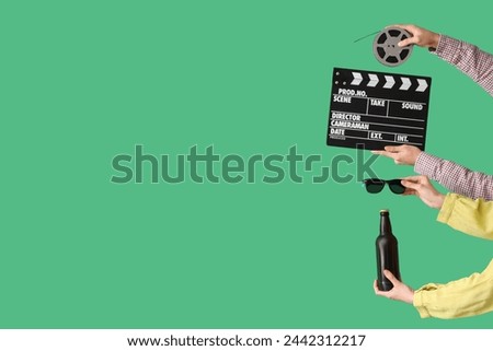 Many hands with movie clapper, beer and film reel on green background