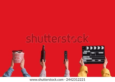 Many hands with bucket of popcorn, movie clapper and beer on red background