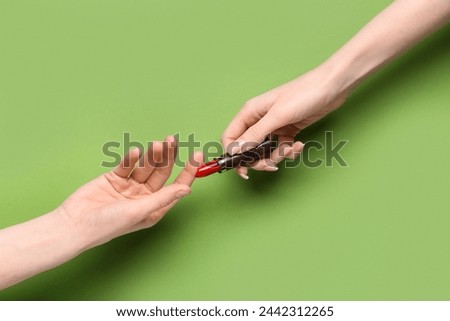 Female hands with red lipstick on green background