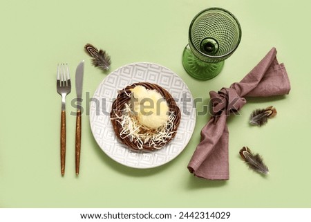 Beautiful table setting with chick and feathers on green background. Easter celebration