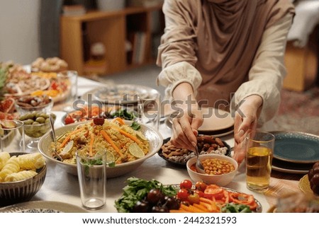 Unrecognizable Woman in Hijab Setting Festive Table For Eid Al-Fitr Royalty-Free Stock Photo #2442321593