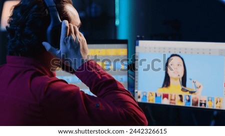Freelancer editing images lighting and color balance, working in home studio while enjoying music. Photographer using headphones to listen favorite songs while using retouching software