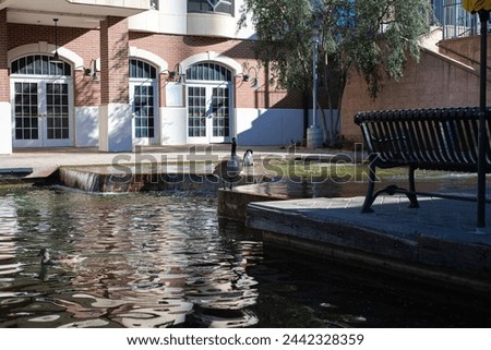 Water front buildings, restaurants, metal bench and ducks along canal in Bricktown, Entertainment District, Oklahoma City, travel destination and tourist attractions. USA