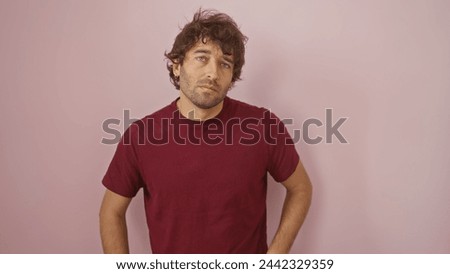 Handsome young hispanic man with a beard standing against an isolated pink wall background