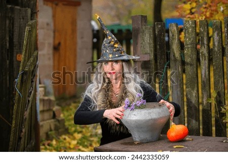 Halloween girl with a magic bowler hat in a witch hat performs witchcraft against an old creepy background.