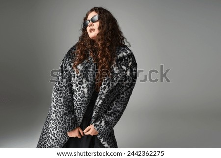 alluring plus size woman in leopard fur coat and sunglasses leaning forward and looking to side