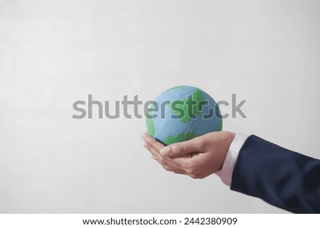 Woman's hand holding the globe, wearing a suit, white background