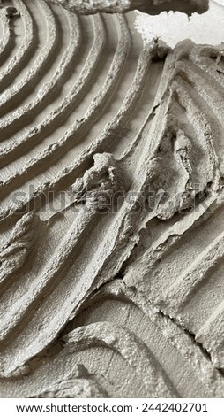 Tile glue with a toothed spatula. Adhesive background. Cement wall vertical photo Royalty-Free Stock Photo #2442402701