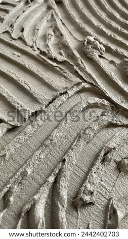 Tile glue with a toothed spatula. Adhesive background. Cement wall vertical photo Royalty-Free Stock Photo #2442402703