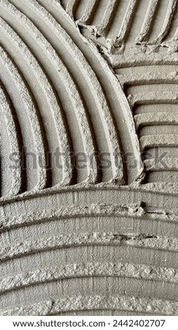 Tile glue with a toothed spatula. Adhesive background. Cement wall vertical photo Royalty-Free Stock Photo #2442402707