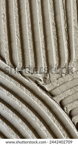 Tile glue with a toothed spatula. Adhesive background. Cement wall vertical photo Royalty-Free Stock Photo #2442402709