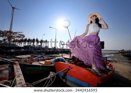 Female model posing on the on damaged fisherman boat in abandoned pier. Fashion style posing.