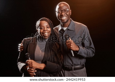 Portrait of two African American performers on stage looking at camera with spotlight
