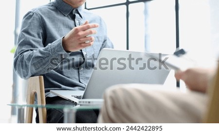 Close-up discussion of documents at a coffee table with a laptop in the background