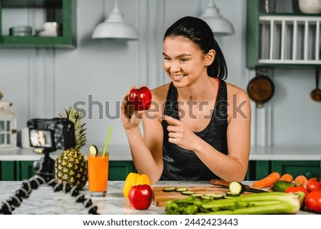 Happy caucasian food blogger showing fruits on the camera in the kitchen. Female athlete vlogging broadcasting on live about dieting, healthy eating, slimming, vegetarianism