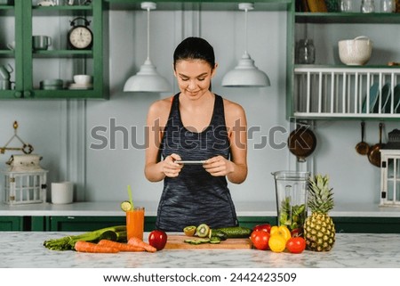 Slim young woman taking photo while cooking healthy vegetarian food with vegetables and fruits in the kitchen. Food vlogging blogging concept. Diet and slimming