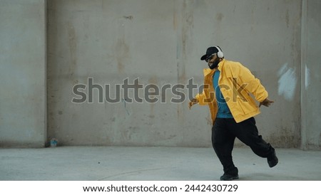 Hipster shows or practicing footstep at street, urban city. Motion shot of young stylish break dancer moving and stretch arm and leg. Outdoor sport 2024. Gray background. Hip hop fashion. Endeavor.