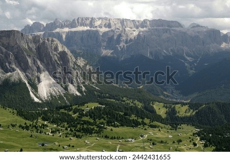 Landscape photo with a panoramic view of mountains and meadows with trees against a cloudy stormy sky in Dolomites, South Tyrol region, Italy Royalty-Free Stock Photo #2442431655