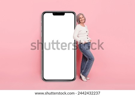 Full size photo of attractive senior woman vertical big smartphone screen eshop wear trendy white clothes isolated on pink color background