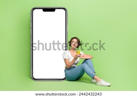 Full body photo of pretty minded lady sit floor use smart phone look empty space information blank isolated on green color background