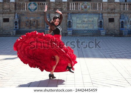 Beautiful woman dancing flamenco in a square in Seville, Spain. She is wearing a typical red and black gypsy dress and dancing flamenco with a lot of art. Flamenco, cultural heritage of humanity Royalty-Free Stock Photo #2442445459