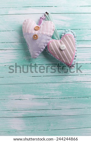 Two textile hearts  on aqua wooden background. Valentine day background. Selective focus is on right heart.