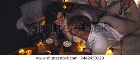 Banner. Romantic surprise for girlfriend or boyfriend for Saint Valentine's Day. Bedroom prepared for watching movies decorated with lights, candles. Cozy home Christmas atmosphere, hot chocolate