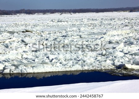 A river with melting cracked ice, snow and frozen water. Winter landscape in cold frosty weather in daytime. Blue sky. Beauty of nature