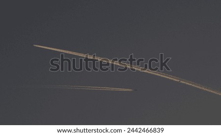 Double smoke lines of the airplanes in dusky sky. Royalty-Free Stock Photo #2442466839