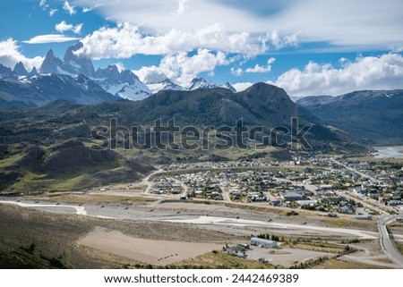 View from above of the city of El Chalten with the imposing Fitz Roy behind. Beautiful view from above of the entire city of El Cahlten in Argentine Patagonia. Imposing Fitz Roy covered in clouds Royalty-Free Stock Photo #2442469389