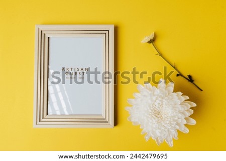 White photo frame and flower is placed on yellow background