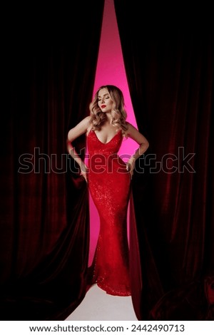 A caucasian woman in a glittering red gown against a dark backdrop. Concetp fashion or luxury brand advertisements. Concept: elegance, luxury fashion. 