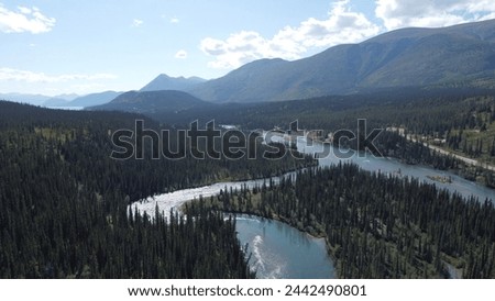 Aerial view of a river winding through a verdant forested valley with mountains rising in the distance in British Columbia, Canada.