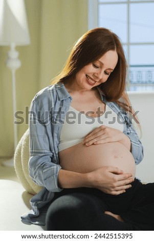 Pregnancy motherhood people expectation future. Pregnant woman touching big belly sitting on couch at home. Girl hugging her tummy enjoying pregnancy. Maternity tenderness parenthood new life concept Royalty-Free Stock Photo #2442515395