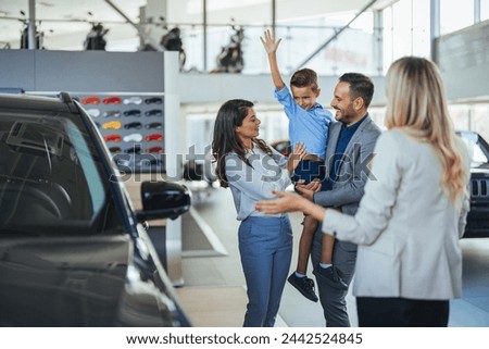 Family in a car dealership. Happy family came to an agreement with a car salesperson at a meeting in a showroom. Happy family choosing a new car in a showroom
