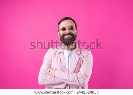 Bearded man dressed in a pink jacket with glasses. Emotional studio portrait. Royalty-Free Stock Photo #2442524859