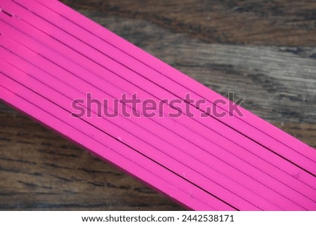Striking image with a pink folding rule lying diagonally in the image. The background is a dark solid wooden table. GoranOfSweden Royalty-Free Stock Photo #2442538171