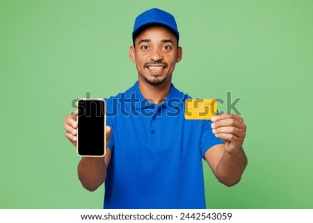 Delivery guy employee man wears blue cap t-shirt uniform workwear work as dealer courier hold credit bank card use blank screen mobile cell phone isolated on plain green background. Service concept