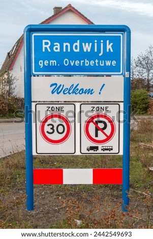 Place name sign for the village of Randwijk, municipality of Overbetuwe, the Netherlands, with the text 'welcome' under it (also no parking for trucks or buses and a speed limit of 30 km per hour)
