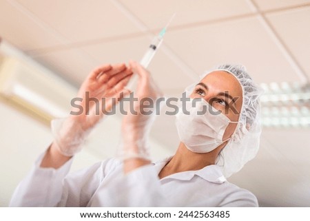 Young nurse in the treatment room prepares a syringe for injection, filling in with medicine