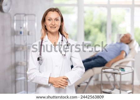 There is medical woman employee in office. Unrecognizable mature male patient sitting in chair in background. Private outpatient practice. Individual approach to treatment Royalty-Free Stock Photo #2442563809