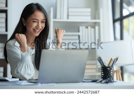 Asian businesswoman, office worker happy and cheerful while receiving recognition on laptop computer, expressing excitement over success and company annual bonus. Success concept.