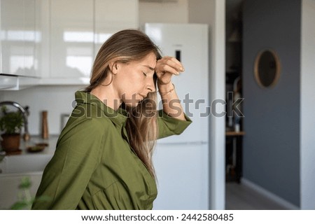 Unwell tired middle aged woman feeling head hurt rubbing forehead standing with closed eyes at home. Unhealthy exhausted female suffering from migraine, head pain, headache, cephalalgia, dizziness. Royalty-Free Stock Photo #2442580485