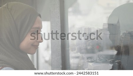 Image of smiling asian woman in hijab looking through window over cityscape. out and about in the city, digitally generated image.