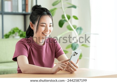 A young Japanese woman using a smartphone in the living room