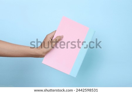 Woman holding pink book with blank cover for mockup isolated on blue background